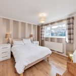 Modern bedroom with striped walls and wooden floor