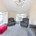 Modern living room with grey sofas and pink ottoman.