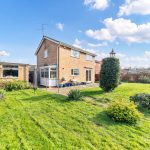 Spacious garden and brick house under clear sky.