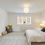 Spacious bedroom with modern decor and large window.