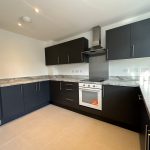 Modern kitchen with dark cabinets and marble counters.