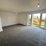 Spacious living room with carpet and garden view.