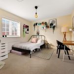 Cosy bedroom with bed, desk, and shelves.