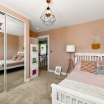 Cosy bedroom with modern decor and mirrored wardrobe.