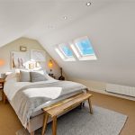 Bright attic bedroom with skylights and modern decor.
