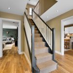 Modern hallway with staircase, wooden flooring, adjacent rooms visible.