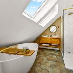 Modern attic bathroom with skylight and freestanding tub.