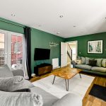 Modern living room with green walls and grey sofa.