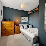 Modern bedroom with wooden drawers and artwork