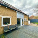 Brown brick house with garden and patio deck.