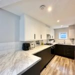 Modern kitchen with marble countertops and appliances.