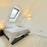 Minimalist attic bedroom with skylight and double bed.