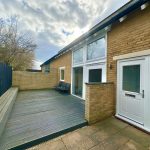 Modern patio with wooden benches and brick wall.