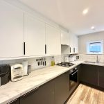 Modern kitchen with appliances and marble countertop.