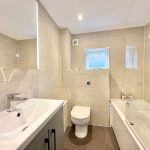 Modern bathroom with beige tiled walls.