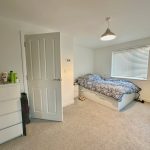 Modern bedroom with bed and dresser in natural light.
