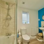 Modern bathroom with shower, bathtub, and sink.