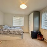 Cosy bedroom with bed, wardrobe, and luggage.