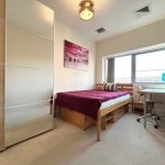 Modern bedroom with bed, desk, wardrobe, and artwork.