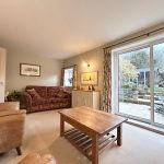 Cosy living room overlooking garden through glass doors.