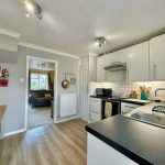 Modern kitchen with wooden floor and white cabinets.
