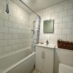 Modern white bathroom with tiles and vanity unit.