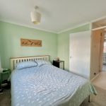 Pastel green bedroom with double bed and decor.