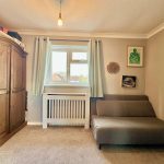 Cosy bedroom with sofa, wardrobe, and window view.