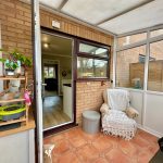 Conservatory with armchair and open door to house.