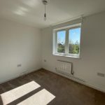 Empty room with window and carpeted floor.