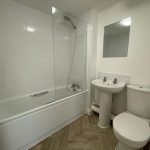 Modern bathroom with bathtub, sink, toilet, and mirror.