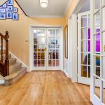 Bright hallway with wooden floor and stairs.