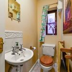 Small restroom with sink, toilet, and floral curtain.