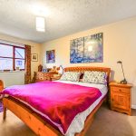Cosy bedroom with wooden furniture and colourful decor.