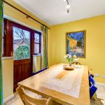 Bright dining room with yellow walls and garden view.