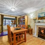 Cosy dining room with bookshelf and fireplace.
