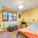 Cosy bedroom with yellow walls and decorative furniture.