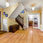 Spacious hallway with staircase, wooden floors.