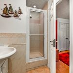 Bathroom with shower, sink, and nautical wall decor.