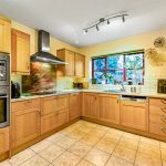 Modern kitchen with wooden cabinets and tiled floor.