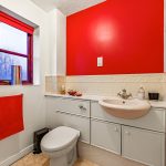 Bathroom with red accents and white cabinets