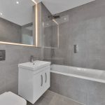 Modern grey tiled bathroom with white fixtures.