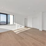 Spacious empty room with wooden floor and large window.