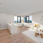 Modern open-plan kitchen and living room with city view.