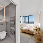 Modern bathroom and bedroom with city view.