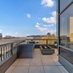 Modern balcony with outdoor seating, urban view.