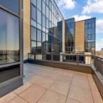 Modern building with large glass windows and terrace.