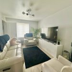 Modern lounge with white sofa and large TV.
