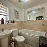 Modern tiled bathroom with shower and mirror.