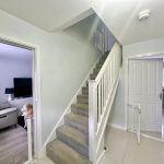 Entryway with staircase and dog in lounge.